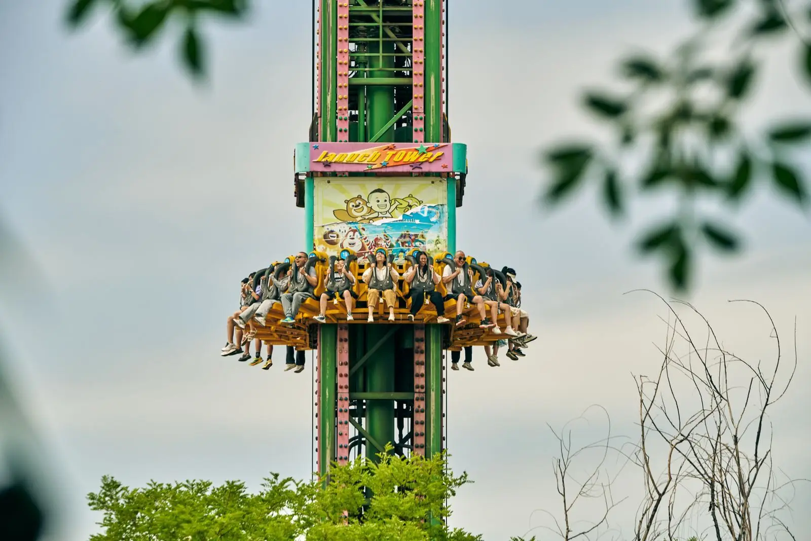 Thrilling drop tower ride with people enjoying an adrenaline rush in an amusement park setting.
