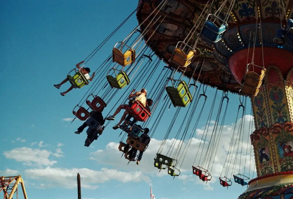 People riding a colorful swing carousel at an amusement park.