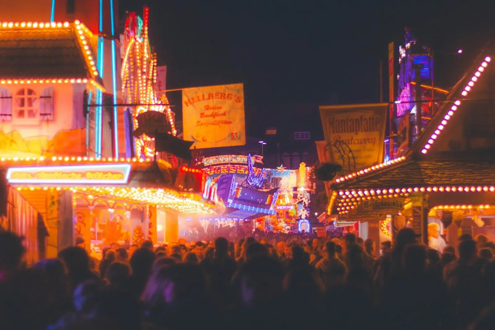 Crowded amusement park at night with bright lights