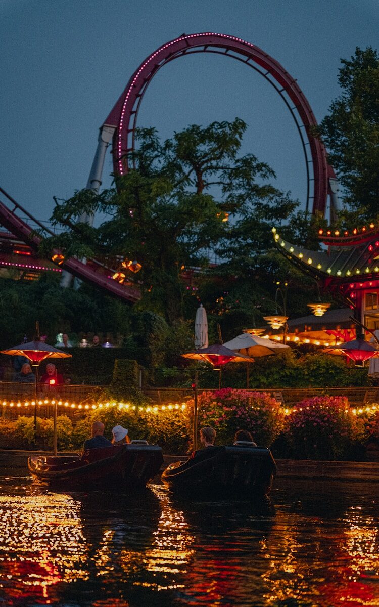 a boat in the water with a ferris wheel in the background with Tivoli Gardens in the background