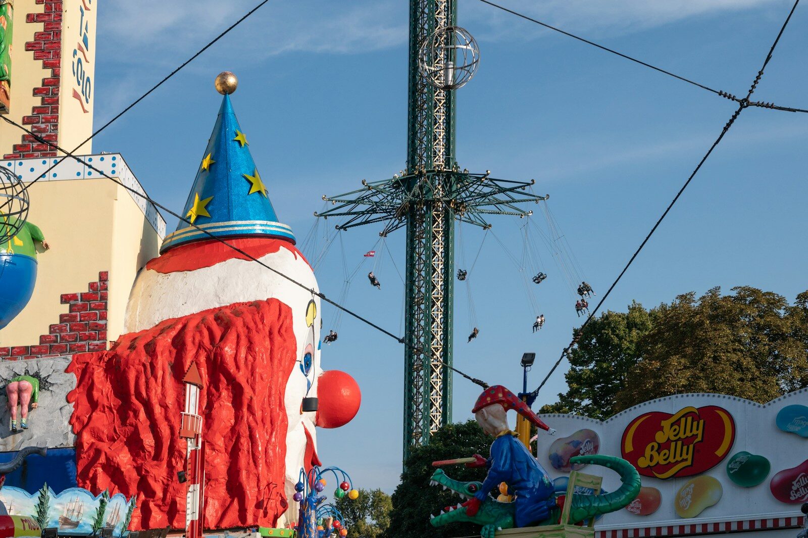 A carnival ride with a large red and white building in the background
