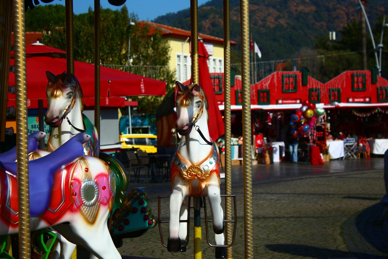 Carousel horses at a sunny outdoor amusement park
