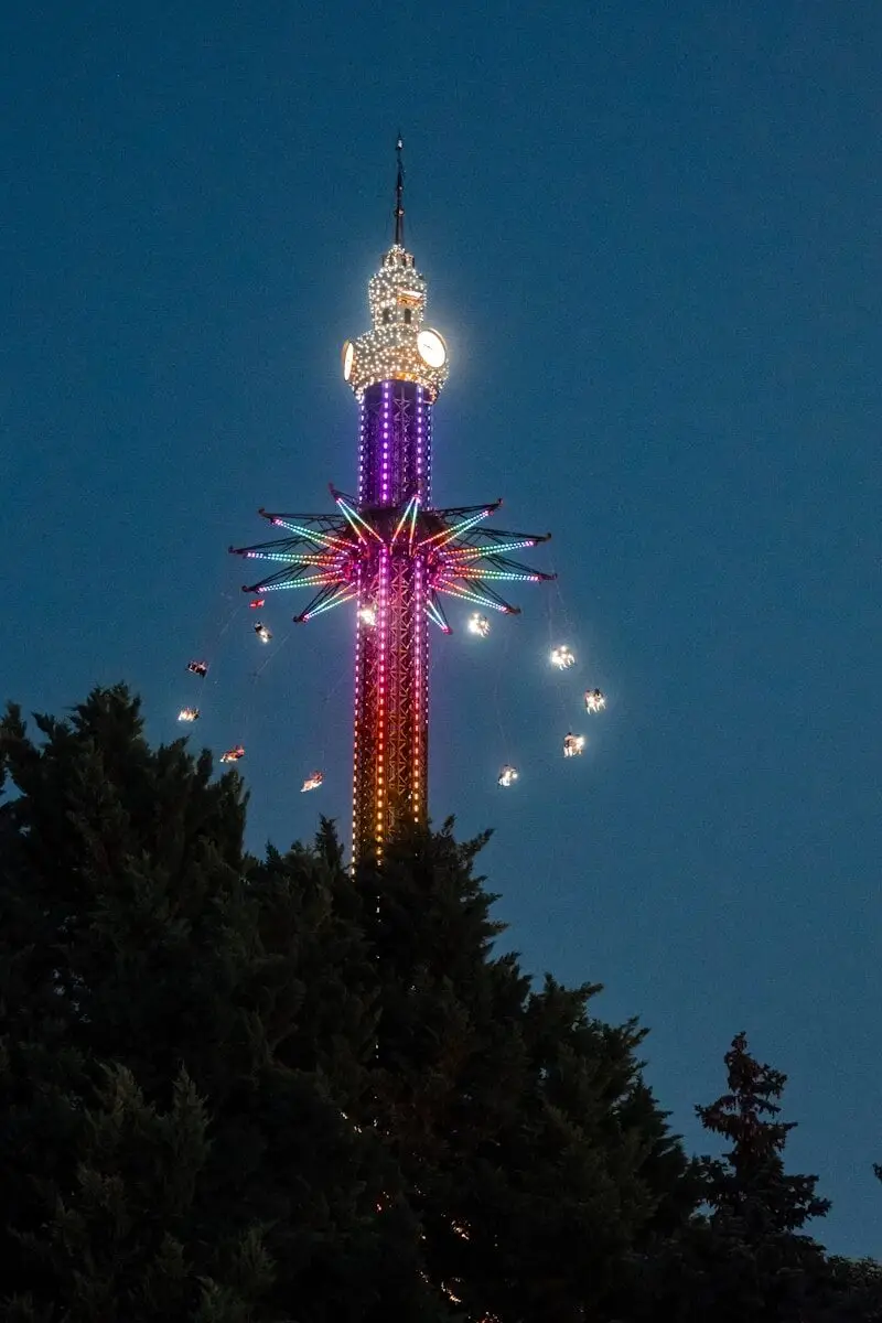 A colorful amusement park swing ride lit up at night.