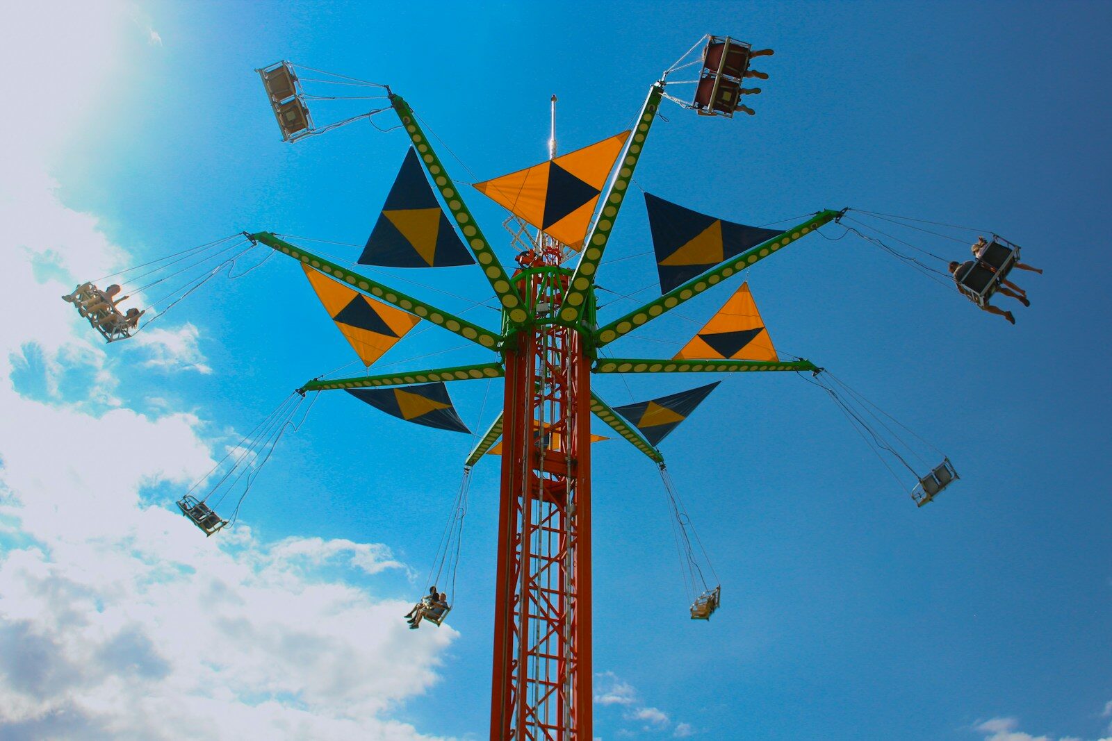Carnival swing ride with people against a bright blue sky