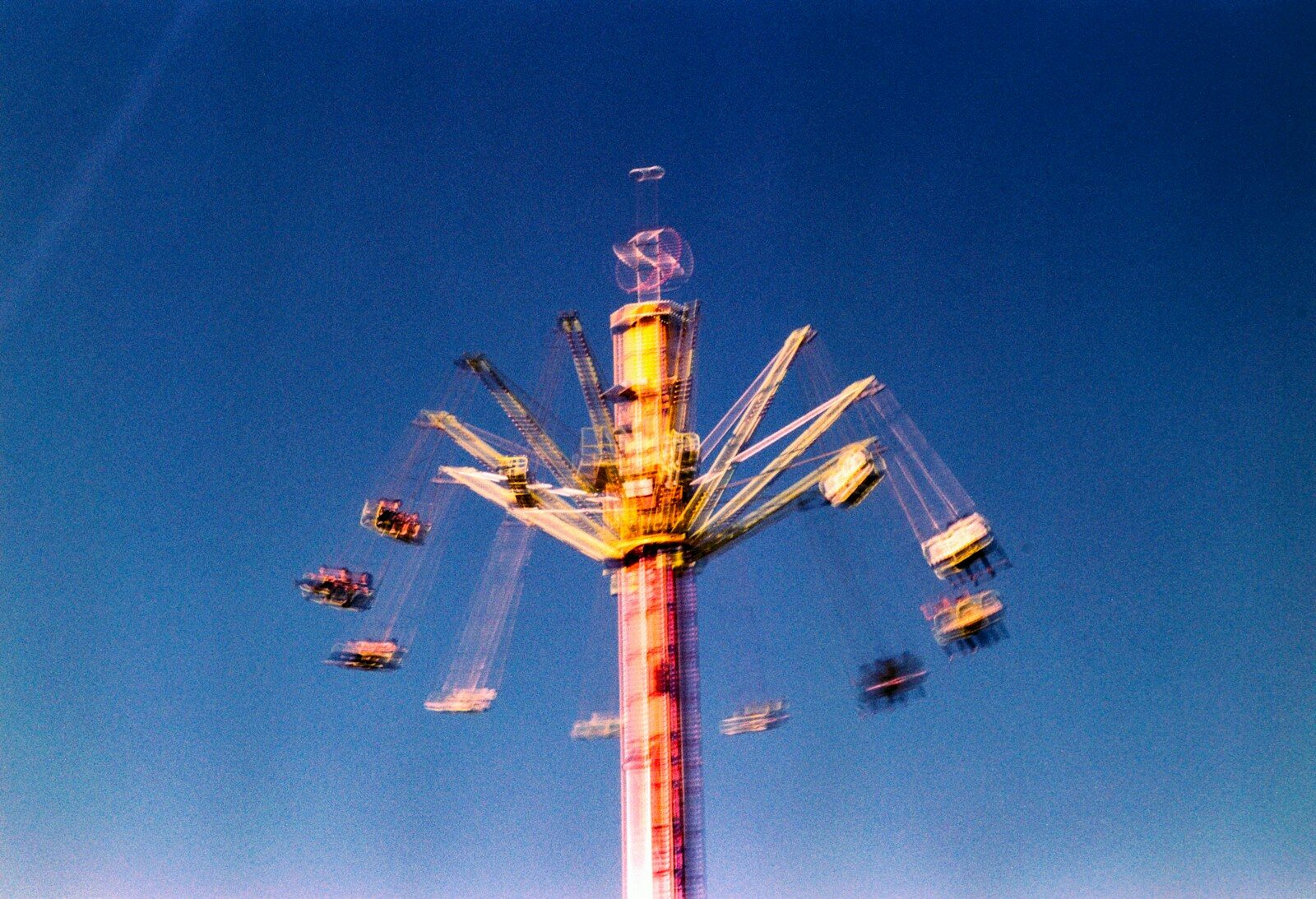Amusement park swing ride in motion against a blue sky