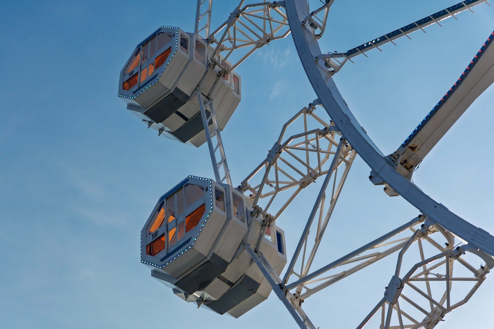 Two ferris wheel cabins against a clear blue sky