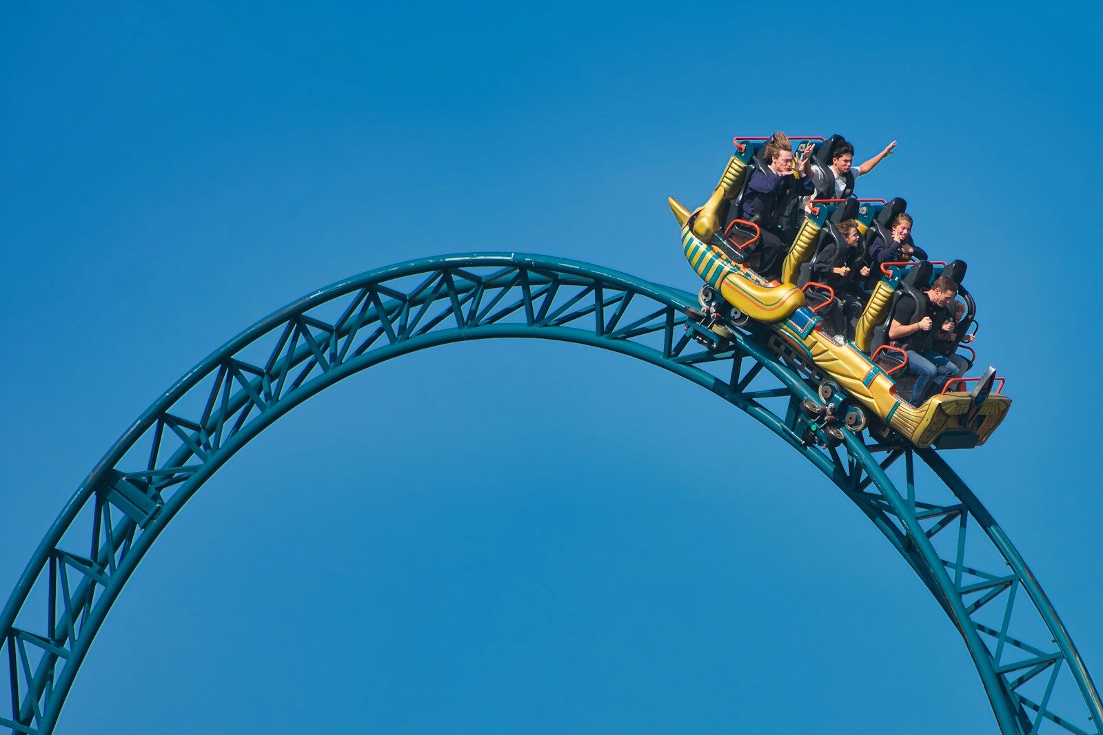 People riding a yellow roller coaster on a loop