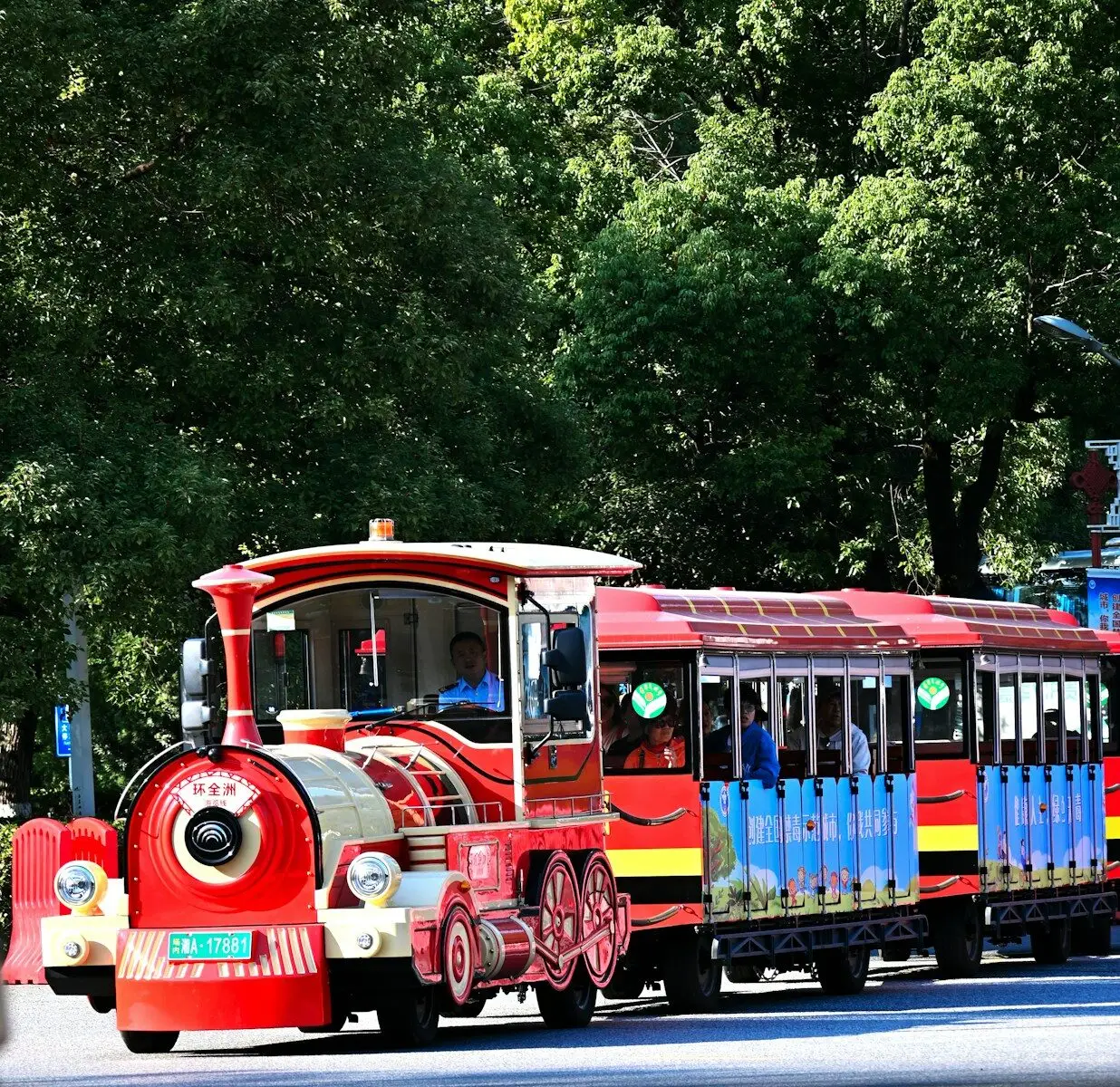 A small red tourist train with open carriages