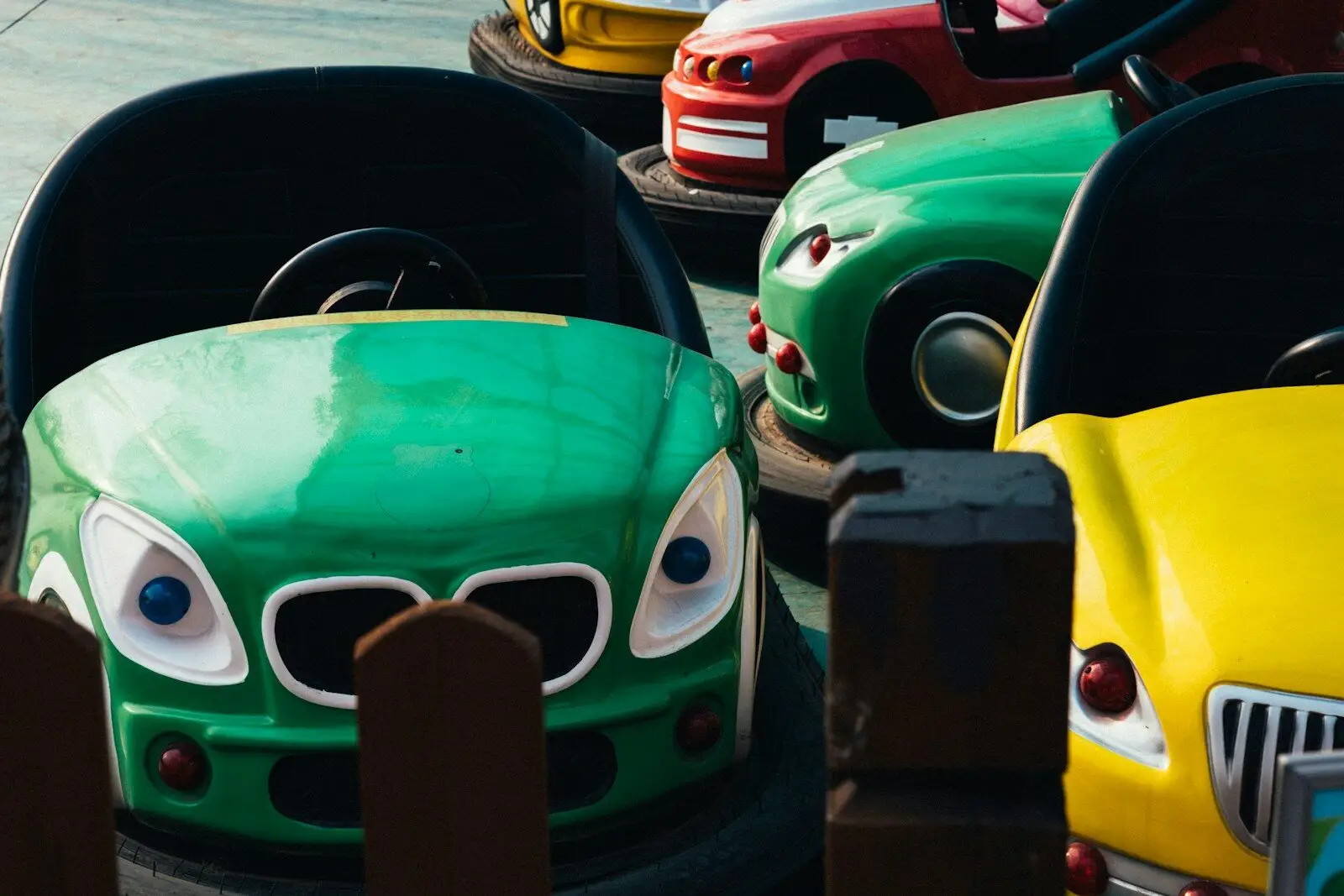 Colorful bumper cars with cartoon faces at an amusement park.