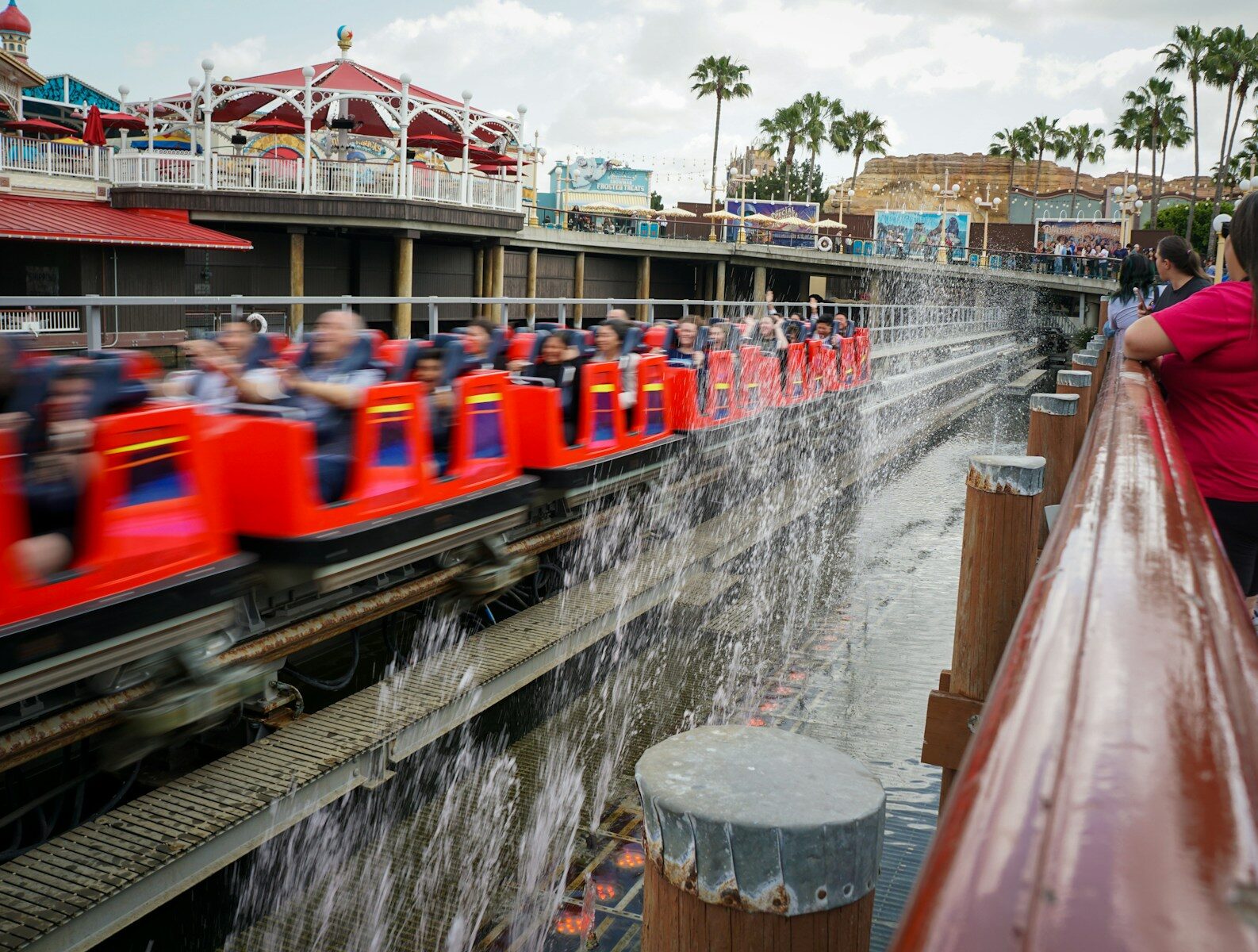 Red roller coaster train splashing through water attraction
