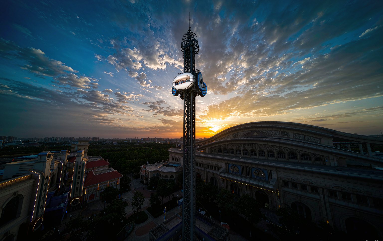 Thrill rides for sale on a manufacturer assembly floor, including a drop tower and frisbee