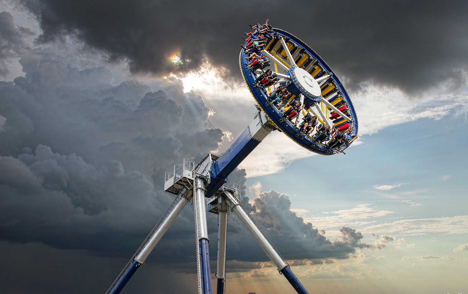 Thrill rides for sale on a manufacturer assembly floor, including a drop tower and frisbee