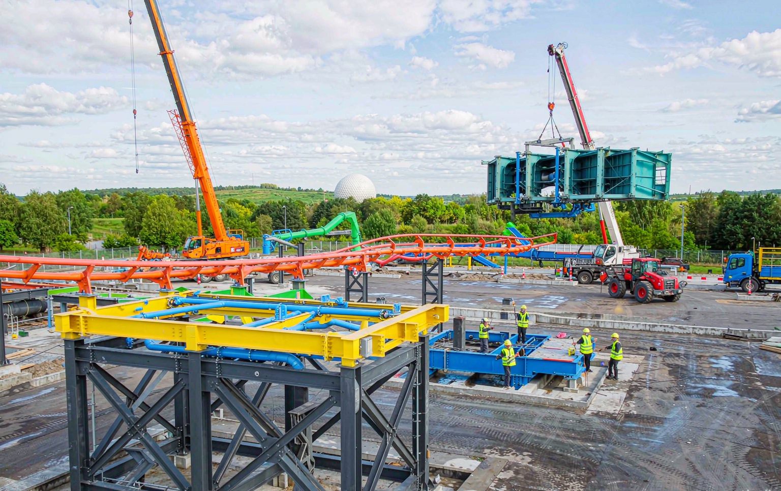 Theme park project under construction with ride foundations, steel components and an installation crew on site