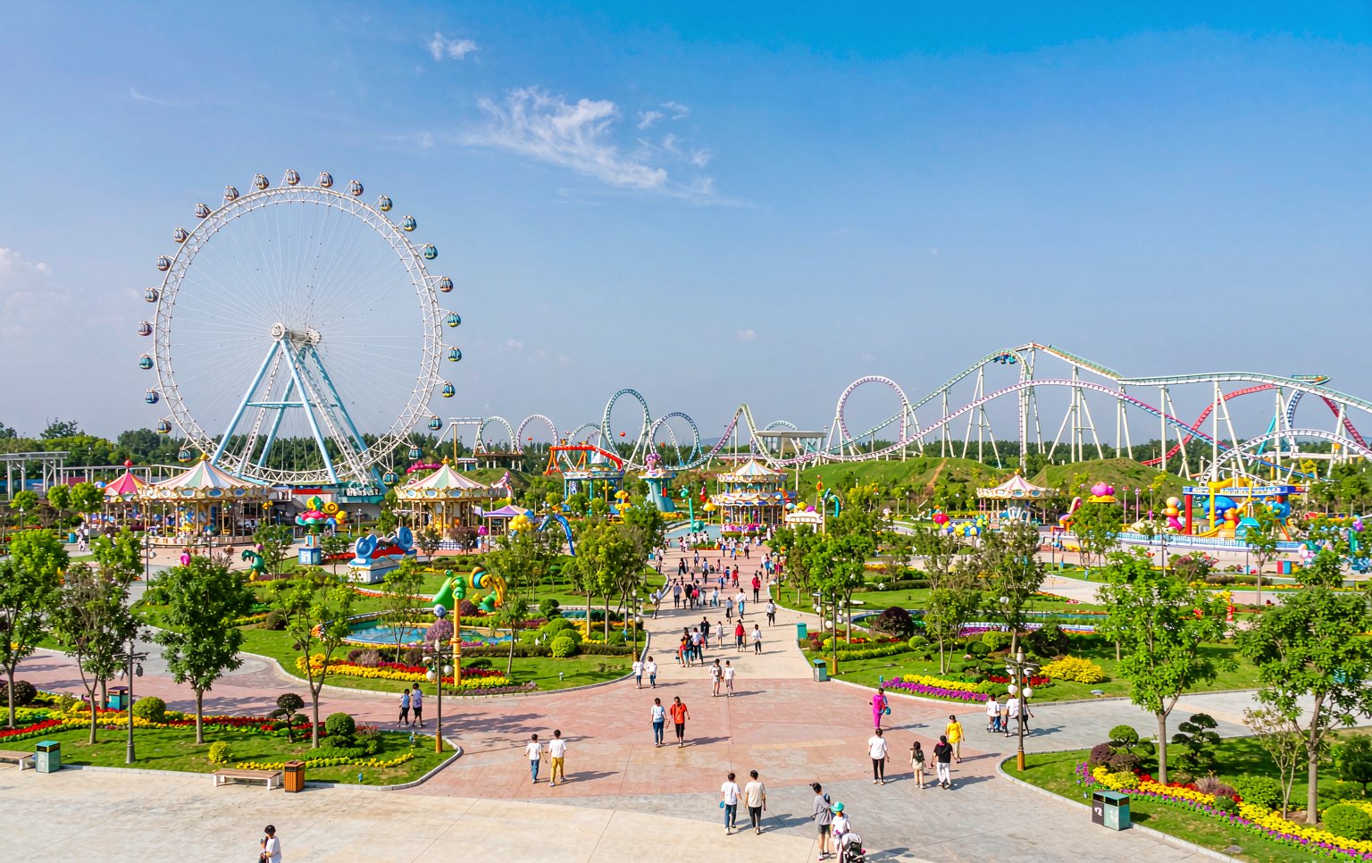 Completed theme park project with multiple rides, landscaping and wide pathways on a sunny day