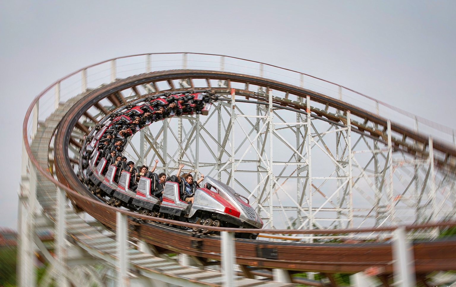 Installation crew assembling steel track sections of a roller coaster for sale at a park construction site