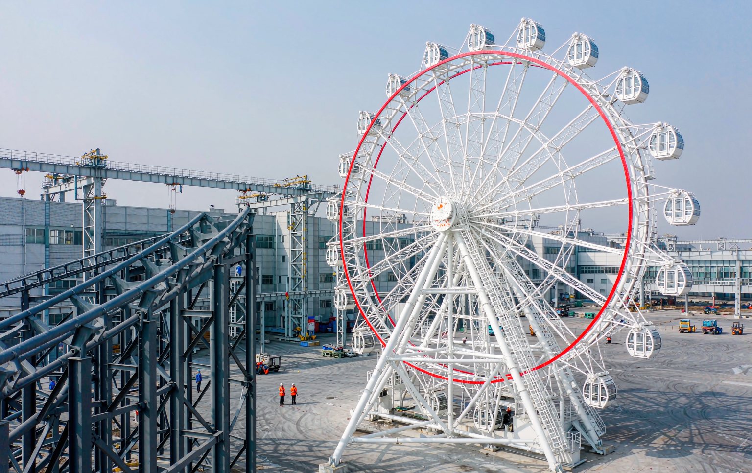 Theme park manufacturers delivering a large Ferris wheel and roller coaster ready for installation