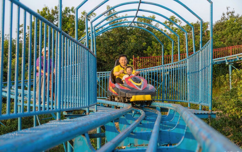 family mountain coaster with parents and children riding a wide sled down gentle curves