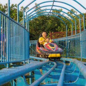 family mountain coaster with parents and children riding a wide sled down gentle curves