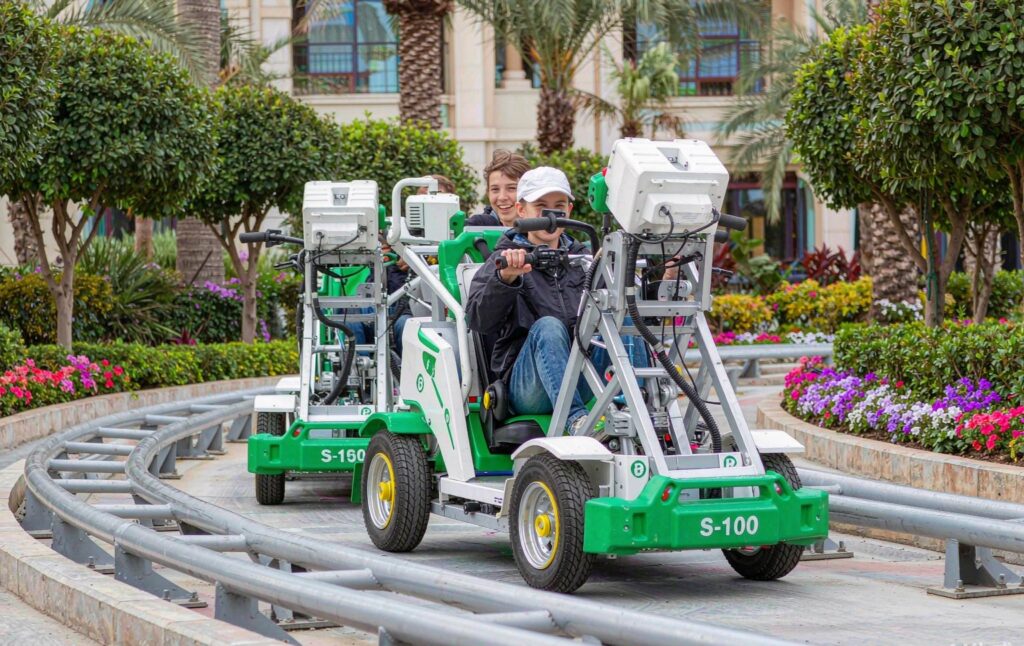electric coaster karts running on a track through a landscaped resort plaza