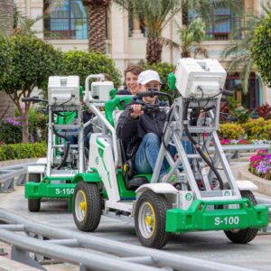 electric coaster karts running on a track through a landscaped resort plaza
