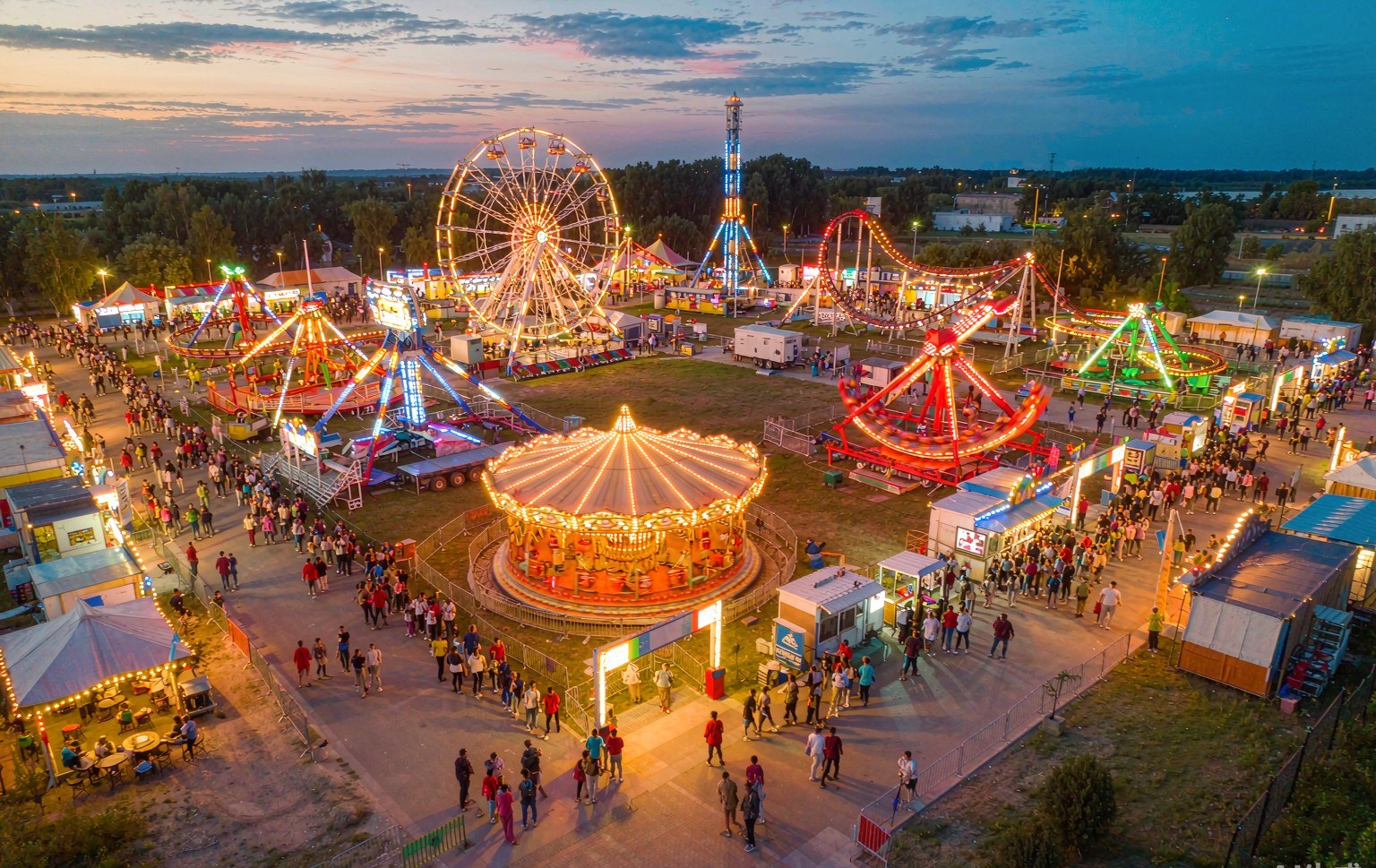 Travelling fairground with mobile carnival rides for sale operating at dusk